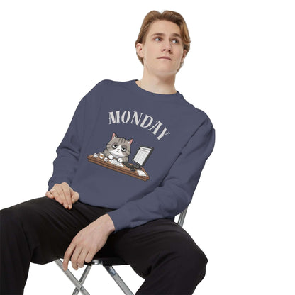 Monday Face Cat Stares Blankly Unisex Crewneck Sweatshirt worn by a man sitting on a chair, featuring a humorous cat design.