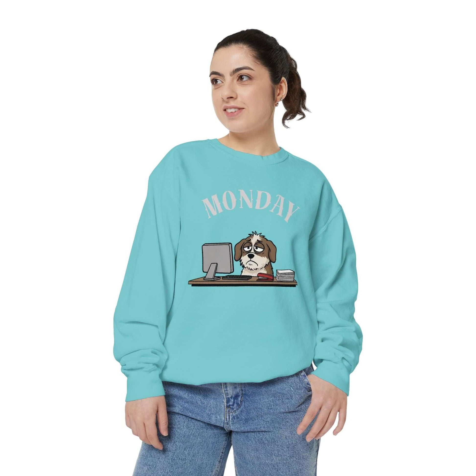 Monday Face Dog Stares Blankly Unisex Crewneck Sweatshirt in teal featuring a dog at a desk with a "MONDAY" banner.